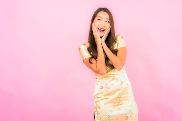 Retrato hermosa joven mujer asiática sonrisa en acción con el concepto de año nuevo chino en la pared de color rosa