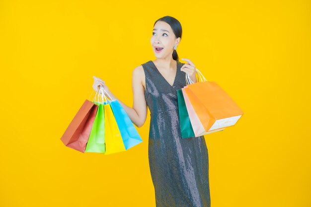 Retrato hermosa joven mujer asiática sonrisa con bolsa de compras en amarillo