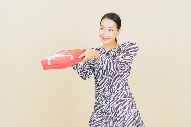 Retrato hermosa joven mujer asiática sonrisa con caja de regalo roja sobre beige