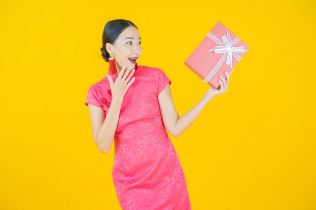 Retrato hermosa joven mujer asiática sonrisa con caja de regalo roja sobre fondo de color