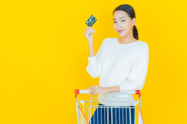 Retrato hermosa joven mujer asiática sonrisa con canasta de supermercado en amarillo