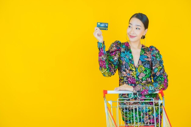 Retrato hermosa joven mujer asiática sonrisa con canasta de supermercado en amarillo