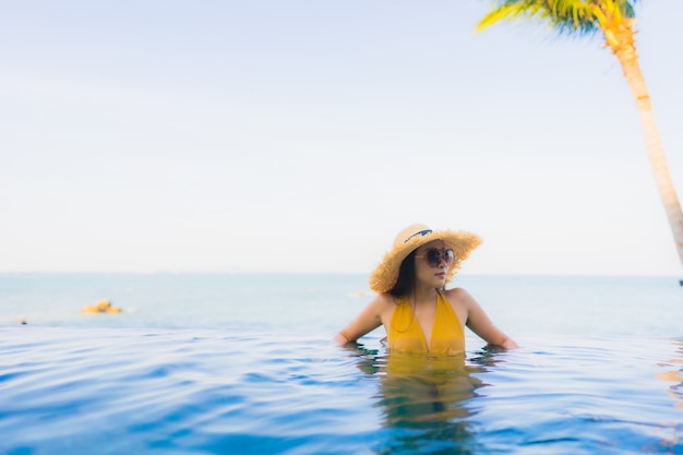 Retrato hermosa joven mujer asiática sonrisa feliz relajarse alrededor de la piscina al aire libre