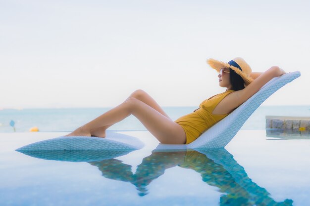 Retrato hermosa joven mujer asiática sonrisa feliz relajarse alrededor de la piscina al aire libre