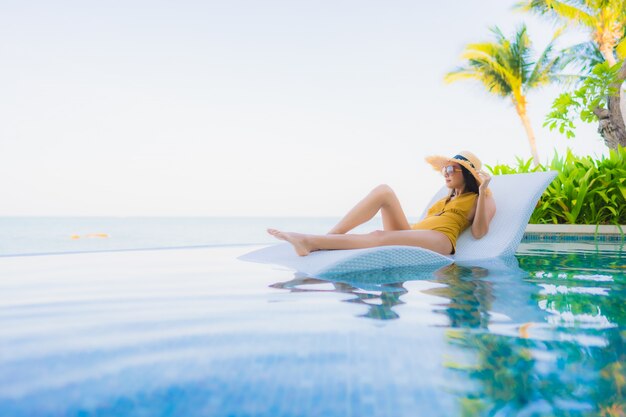 Retrato hermosa joven mujer asiática sonrisa feliz relajarse alrededor de la piscina al aire libre