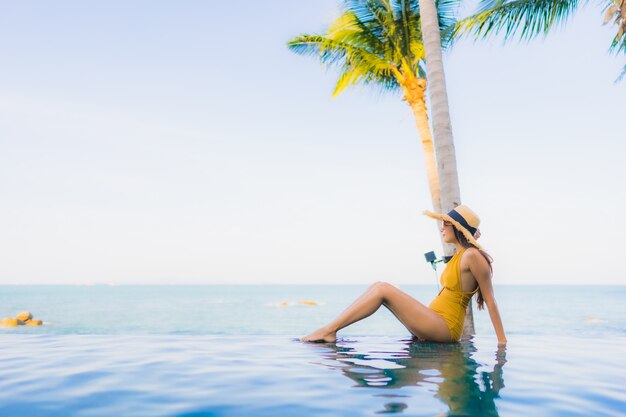 Retrato hermosa joven mujer asiática sonrisa feliz relajarse alrededor de la piscina al aire libre