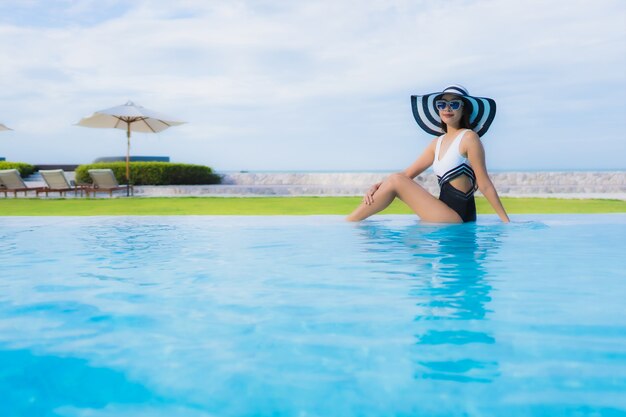 Retrato hermosa joven mujer asiática sonrisa feliz relajarse alrededor de la piscina