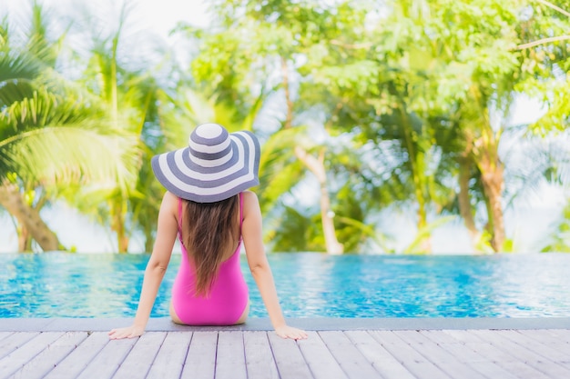 Foto gratuita retrato hermosa joven mujer asiática sonrisa relajarse alrededor de la piscina al aire libre en el hotel resort en viaje de vacaciones de vacaciones