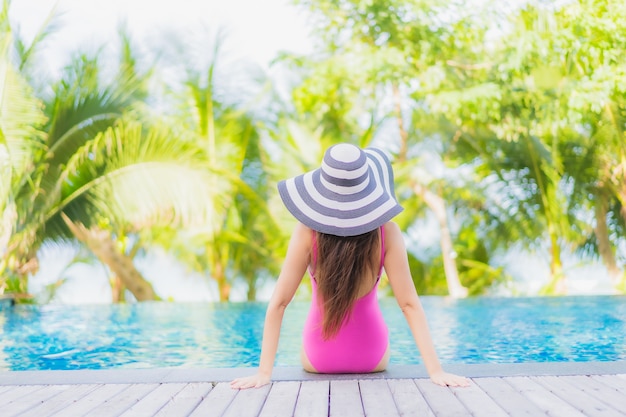 Foto gratuita retrato hermosa joven mujer asiática sonrisa relajarse alrededor de la piscina al aire libre en el hotel resort en viaje de vacaciones de vacaciones