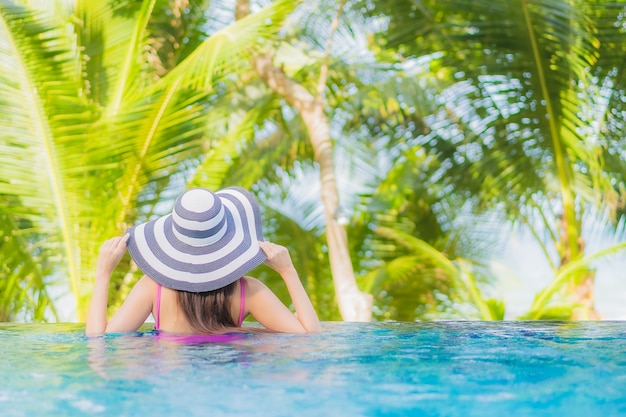 Foto gratuita retrato hermosa joven mujer asiática sonrisa relajarse alrededor de la piscina al aire libre en el hotel resort en viaje de vacaciones de vacaciones