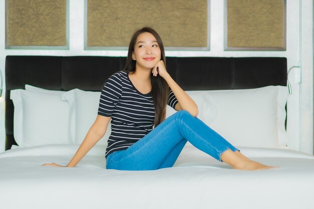 Retrato hermosa joven mujer asiática sonrisa relajarse en la cama en el interior del dormitorio