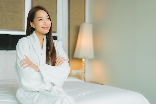 Foto gratuita retrato hermosa joven mujer asiática sonrisa relajarse en la cama en el interior del dormitorio