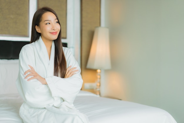 Retrato hermosa joven mujer asiática sonrisa relajarse en la cama en el interior del dormitorio