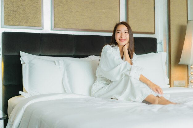 Retrato hermosa joven mujer asiática sonrisa relajarse en la cama en el interior del dormitorio