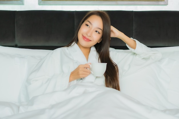 Retrato hermosa joven mujer asiática sonrisa relajarse en la cama en el interior del dormitorio