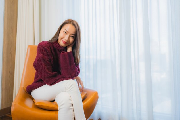 Retrato hermosa joven mujer asiática sonrisa relajarse en el sofá en el interior de la sala de estar