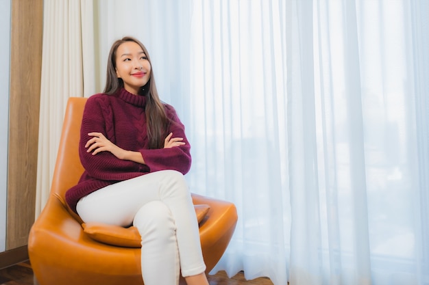 Retrato hermosa joven mujer asiática sonrisa relajarse en el sofá en el interior de la sala de estar