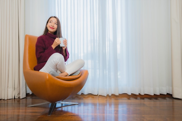 Retrato hermosa joven mujer asiática sonrisa relajarse en el sofá en el interior de la sala de estar