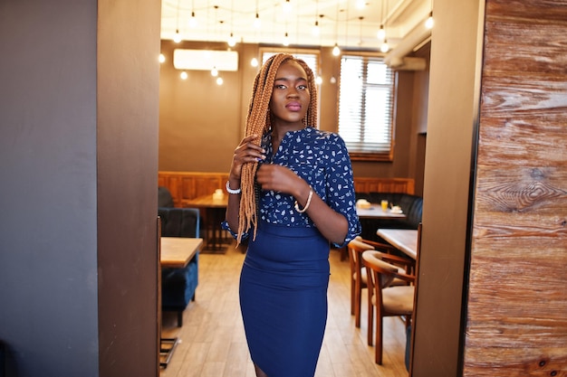 Retrato de una hermosa joven mujer de negocios africana vestida con blusa azul y falda posando en un café