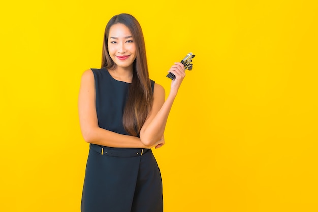 Retrato hermosa joven mujer de negocios asiática con maquillaje cepillo cosmético sobre fondo amarillo