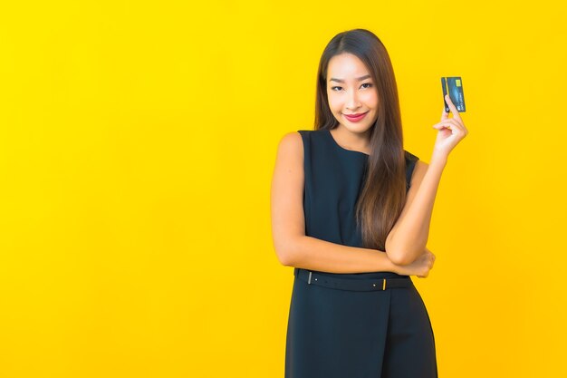 Retrato hermosa joven mujer de negocios asiática con tarjeta de crédito sobre fondo amarillo