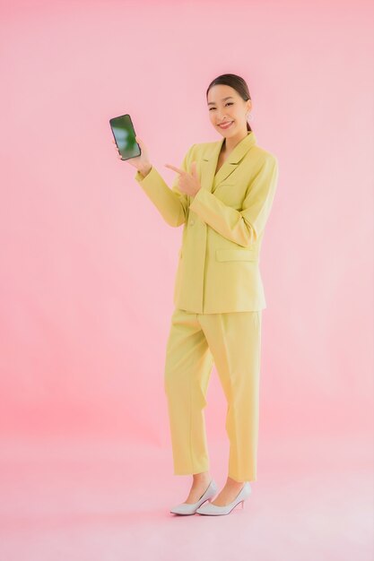 Retrato hermosa joven mujer de negocios asiática utiliza teléfono móvil inteligente con taza de café en color