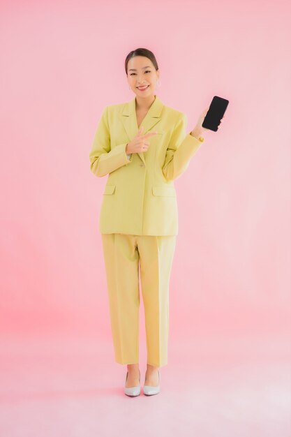 Retrato hermosa joven mujer de negocios asiática utiliza teléfono móvil inteligente con taza de café en color