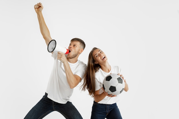 Retrato de la hermosa joven pareja de aficionados al fútbol o al fútbol en el espacio en blanco. Expresión facial, emociones humanas, publicidad, concepto deportivo.