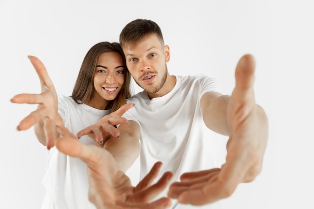 Foto gratuita retrato de la hermosa joven pareja aislado en la pared blanca. expresión facial, emociones humanas, concepto publicitario. copyspace. mujer y hombre de pie tirando de las manos