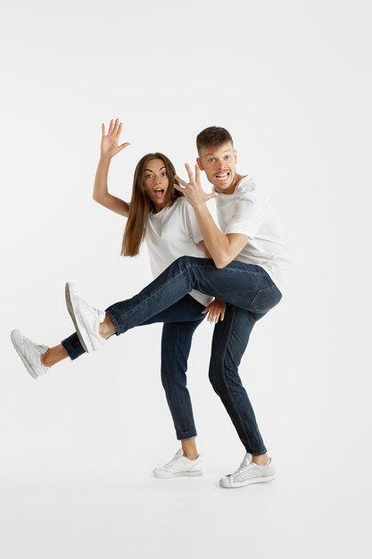 Retrato de la hermosa joven pareja aislado en la pared blanca. Expresión facial, emociones humanas, concepto publicitario. Copyspace. Mujer y hombre saltando, bailando o corriendo juntos.