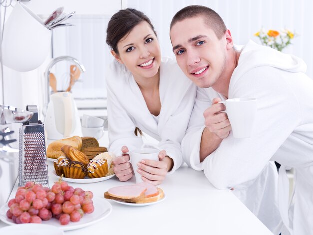 Retrato de hermosa joven pareja sonriente desayunando en el kithen