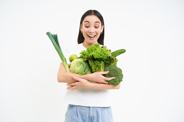 Foto gratuita retrato de una hermosa joven saludable que sostiene vegetales verdes veganos disfruta de comida oránica verde st