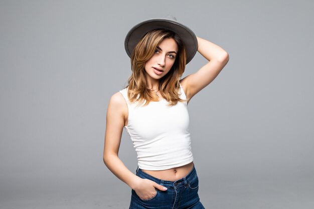 Retrato de una hermosa joven con un sombrero aislado en la pared gris