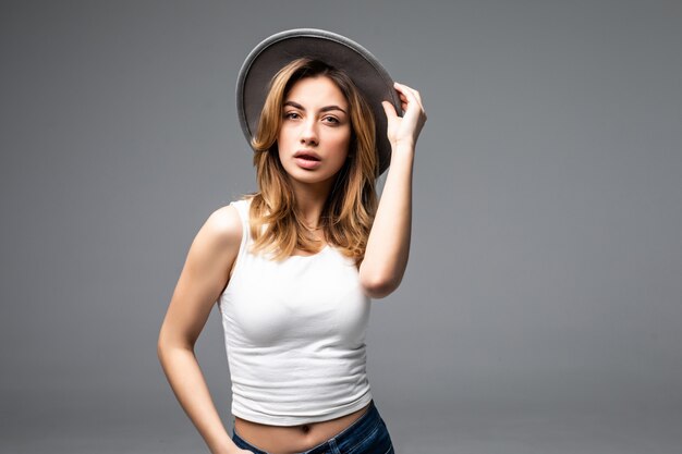 Retrato de una hermosa joven con un sombrero aislado en la pared gris