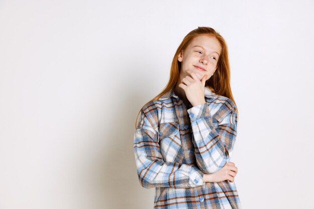 Retrato de una hermosa jovencita en camisa a cuadros posando aislada sobre fondo blanco de estudio