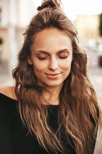 Retrato de la hermosa modelo adolescente linda rubia sin maquillaje en ropa hipster de verano posando en el fondo de la calle. Ojos cerrados