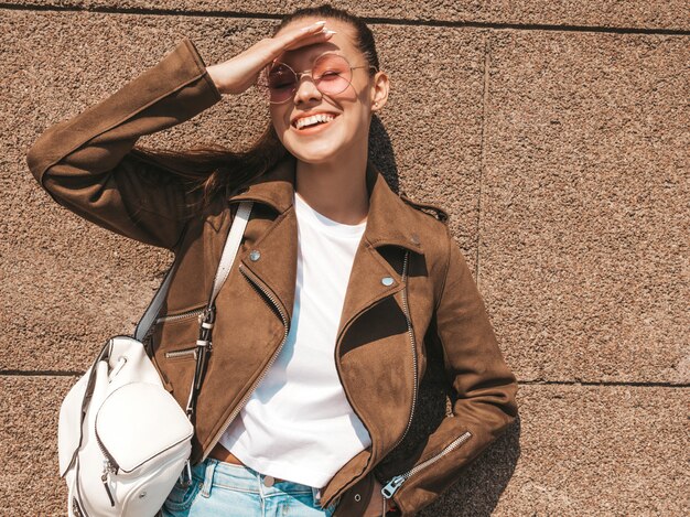 Retrato de la hermosa modelo morena sonriente vestida con ropa de jeans y chaqueta hipster de verano