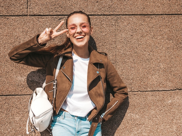 Retrato de la hermosa modelo morena sonriente vestida con ropa de jeans y chaqueta hipster de verano