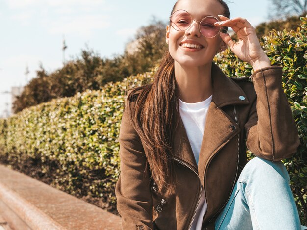 Retrato de la hermosa modelo morena sonriente vestida con ropa de jeans y chaqueta hipster de verano