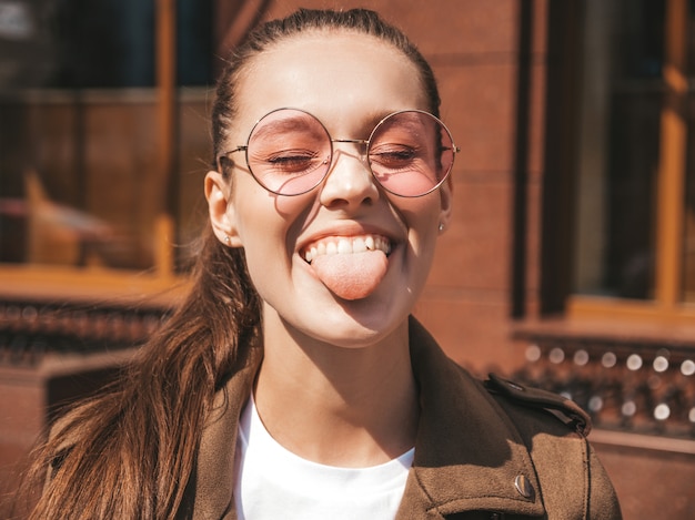 Retrato de la hermosa modelo morena sonriente vestida con ropa de verano hipster chaqueta mostrando su lengua