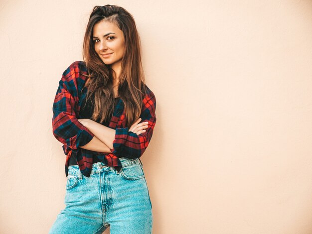 Retrato de hermosa modelo. Mujer sexy vestida con jeans y camisa a cuadros de verano hipster. Chica de moda posando junto a la pared en la calle