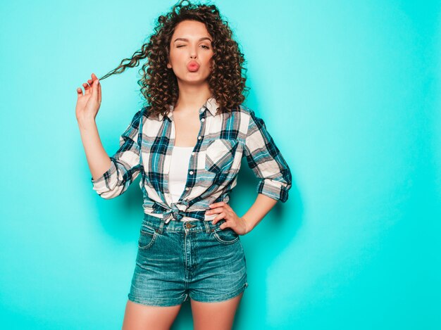 Retrato de hermosa modelo sonriente con peinado afro rizos vestido con ropa hipster de verano. Mujer divertida y positiva de moda hace cara de pato