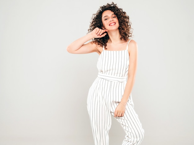 Retrato de hermosa modelo sonriente con peinado afro rizos vestido con ropa hipster de verano. Mujer divertida y positiva de moda