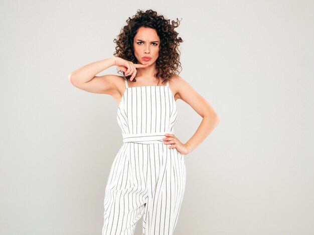 Retrato de hermosa modelo sonriente con peinado afro rizos vestido con ropa hipster de verano. Mujer divertida y positiva de moda