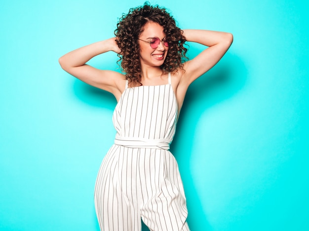 Foto gratuita retrato de hermosa modelo sonriente con peinado afro rizos vestido con ropa hipster de verano. mujer divertida y positiva de moda