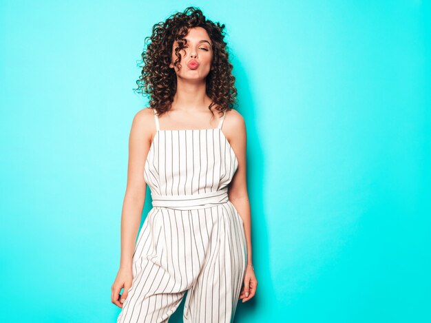 Retrato de hermosa modelo sonriente con peinado afro rizos vestido con ropa hipster de verano. Mujer divertida y positiva de moda