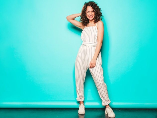 Retrato de hermosa modelo sonriente con peinado afro rizos vestido con ropa hipster de verano. Mujer divertida y positiva de moda