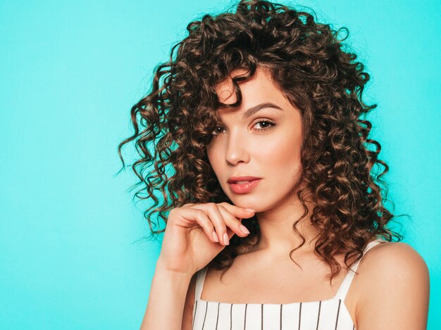 Retrato de hermosa modelo sonriente con peinado afro rizos vestido con ropa hipster de verano. Mujer divertida y positiva de moda