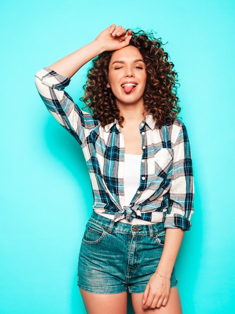 Retrato de hermosa modelo sonriente con peinado afro rizos vestido con ropa hipster de verano. Mujer divertida y positiva de moda