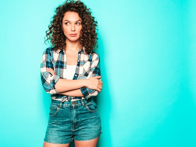 Retrato de hermosa modelo sonriente con peinado afro rizos vestido con ropa hipster de verano. Mujer divertida y positiva de moda